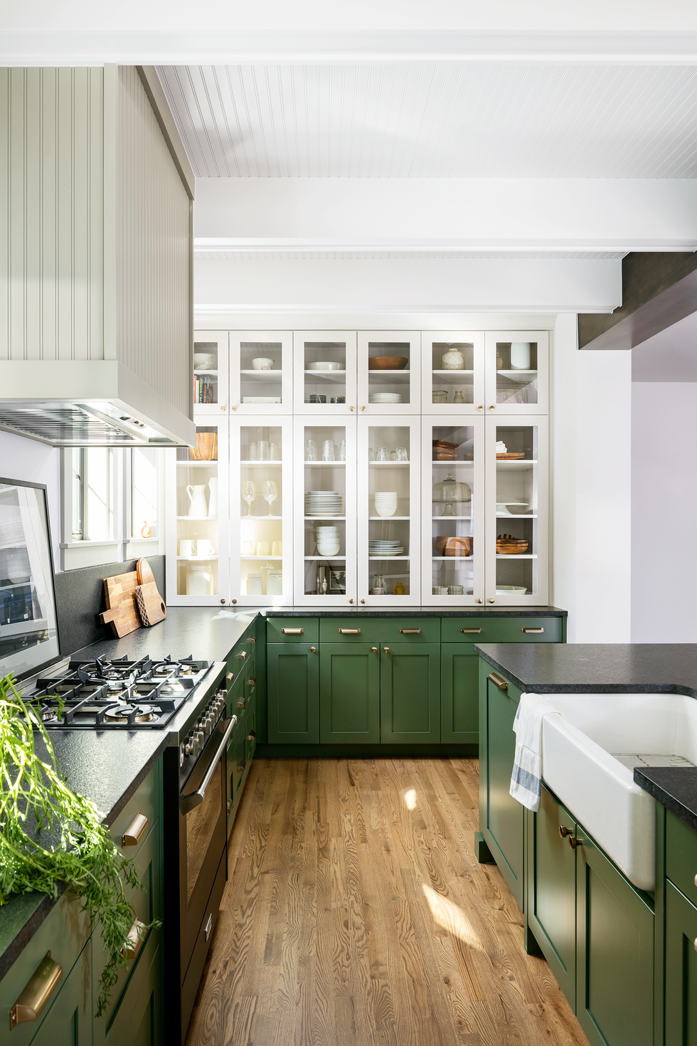 organized kitchen setup by design and build firm forge bow dwellings green lower cabinets, white upper cabinets, glass front cabinets, dishware in cabinets, clean, organized