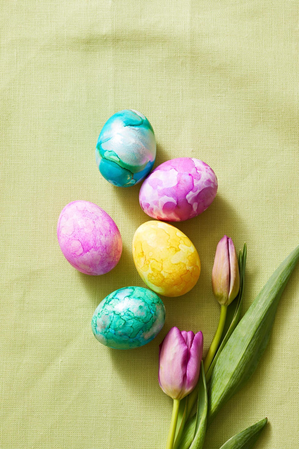 colorful easter eggs and tulips on a light green background
