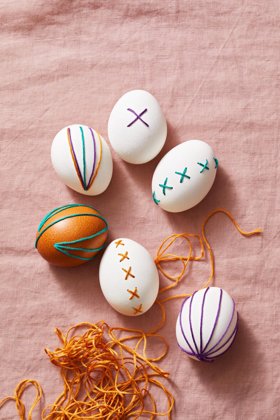 decoratively stitched eggs arranged on a fabric surface