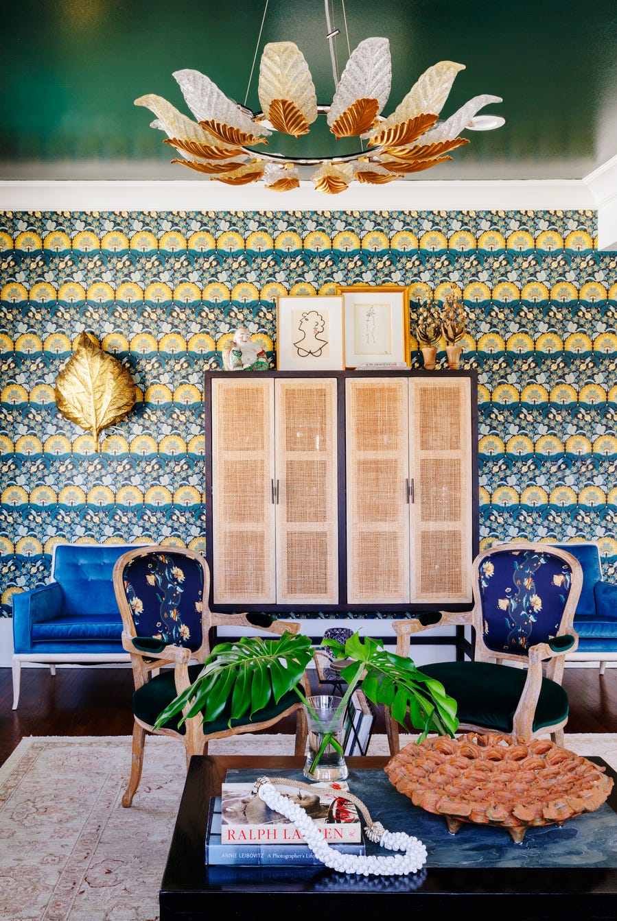 eclectic homewith wallpaper, green painted ceiling, storage cabinet with rattan doors, blue chairs, living room.
