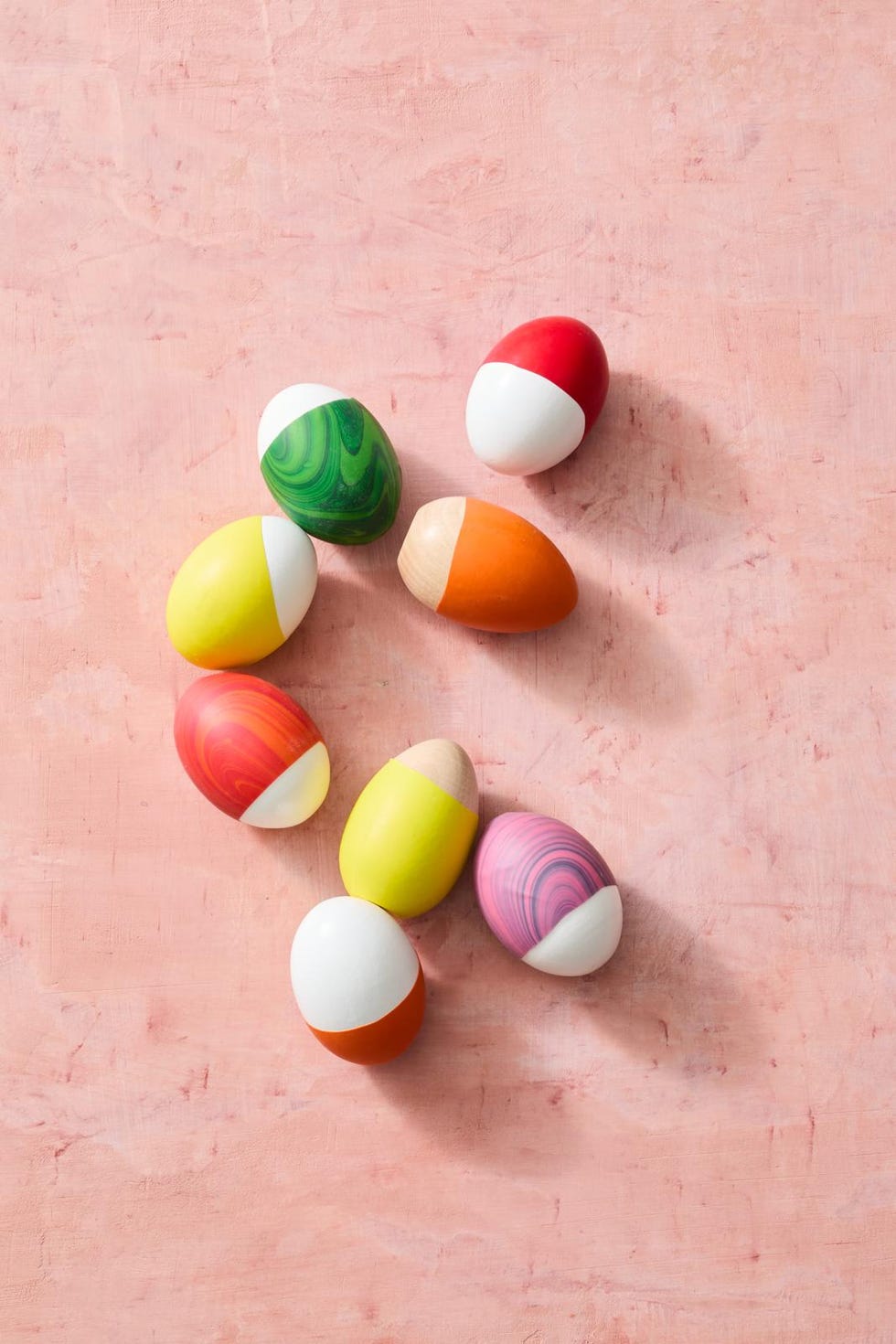 colorful decorative eggs arranged on a light pink background