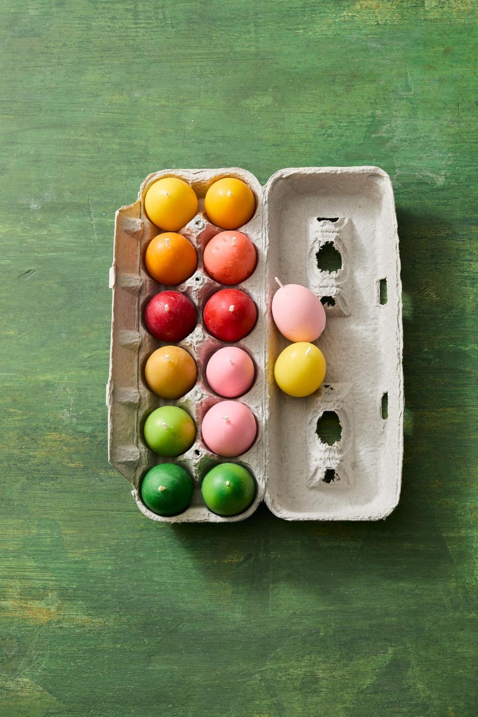 colorful decorative candles resembling eggs in a carton