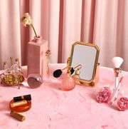 vintage beauty products on pink textured surface in front of pink folded curtain