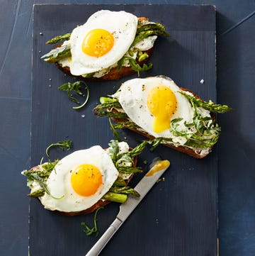 asparagus tartines with herbed ricotta and eggs asparagus tartines with herbed ricotta and sunny side up eggs on a black board