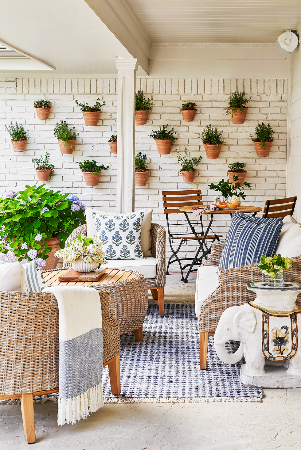 outdoor "living" wall potted plants mounted on white brick wall woven patio furniture, wicker, rattan