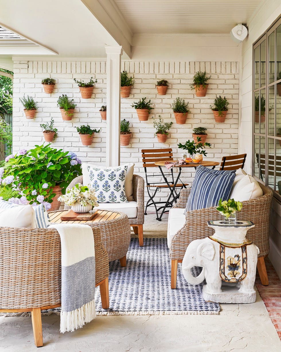 outdoor "living" wall. potted plants mounted on white brick wall. woven patio furniture, wicker, rattan.