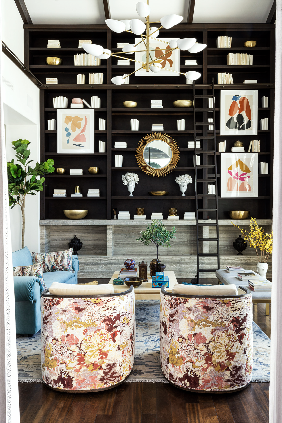 living room with black bookshelves and floral armchairs