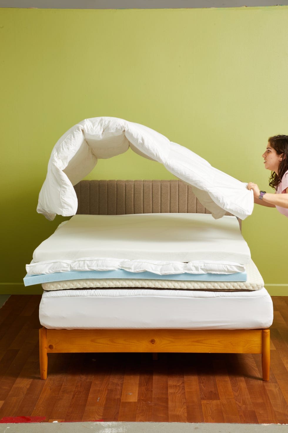 a person adjusts a topper on a bed