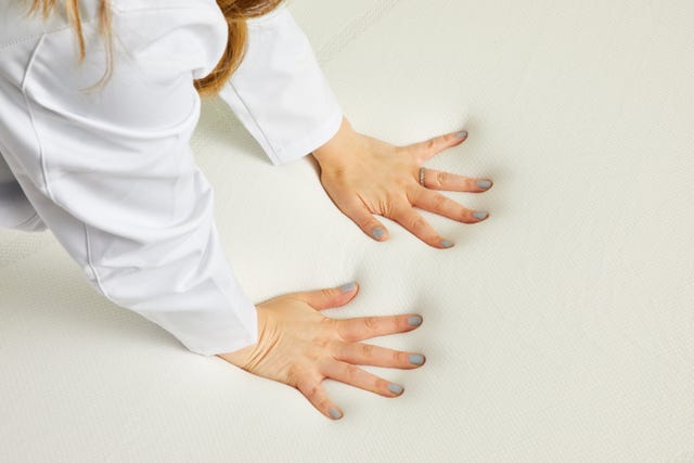 a good housekeeping analyst pushing into a mattress topper to evaluate the foam, good housekeeping's best mattress toppers