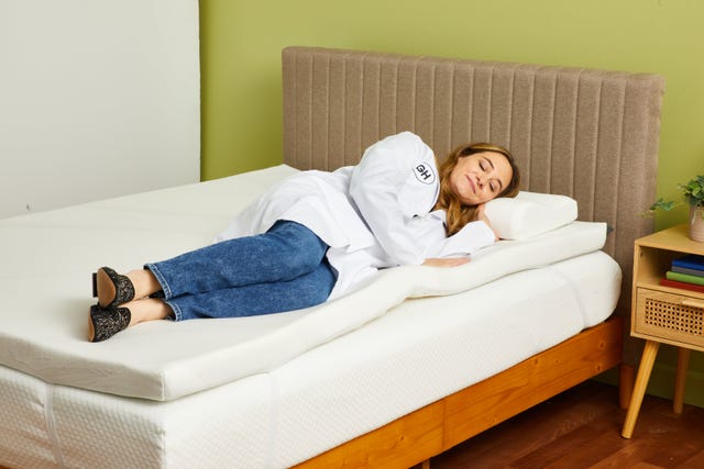 a person lying on a mattress topper on a mattress to test its comfort, good housekeeping's best mattress toppers