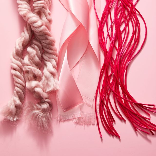 three strands of ribbon and rope with frayed ends in various shades of pink on a pink background