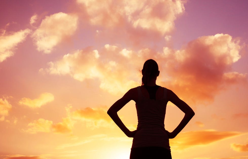 woman standing on the top of the hill watching a beautiful sunset location hawaii