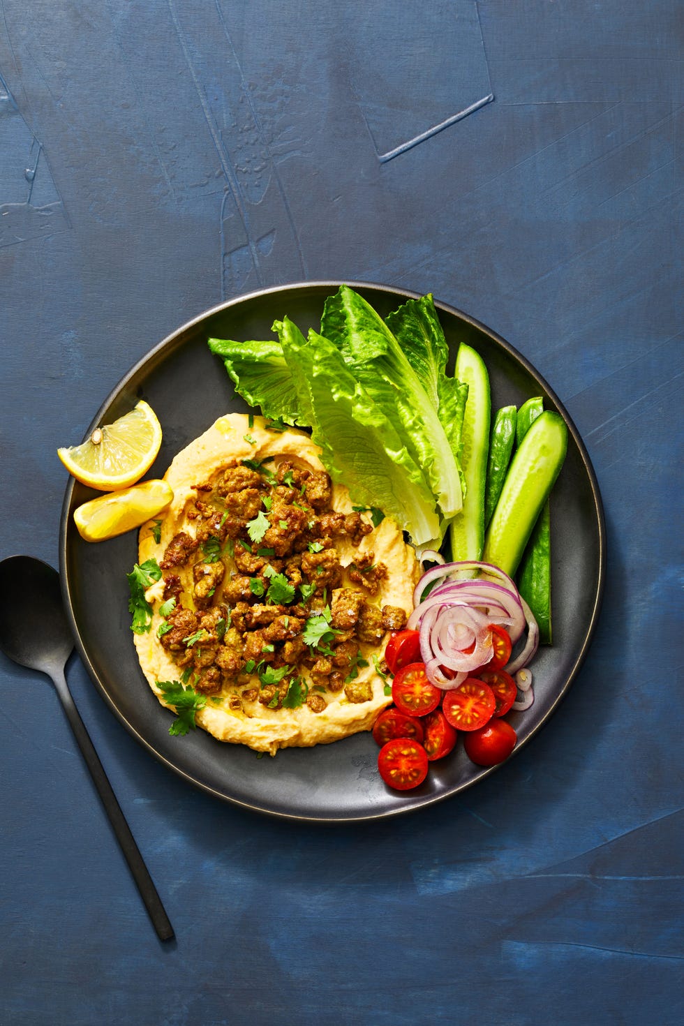 spiced lamb with warm lentil hummus, tomatoes, cucumbers, and lettuce