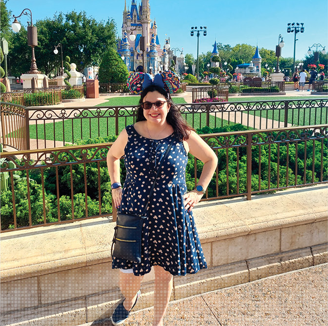 the author wearing mickey dress and ears in front of disney world's cinderella's castle