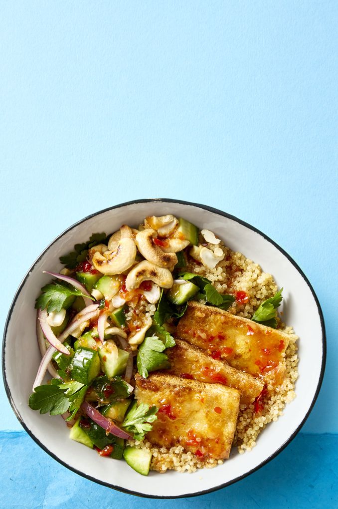 a bowl of crispy tofu slices, chopped cucumber and quinoa in a white bowl