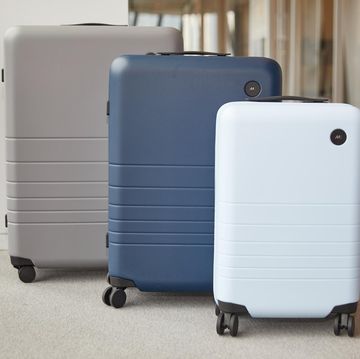three monos suitcases including a light blue carry on case, a blue medium case and a grey checked case lined up in a hallway at the good housekeeping institute