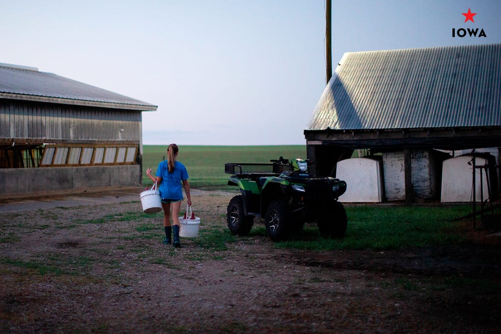 woman walking on farm with buckets of milk in iowa