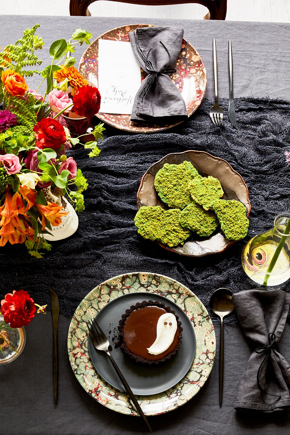 halloween party ideas, gothic tablescape with a black table runner, ghost cupcakes and black utensils