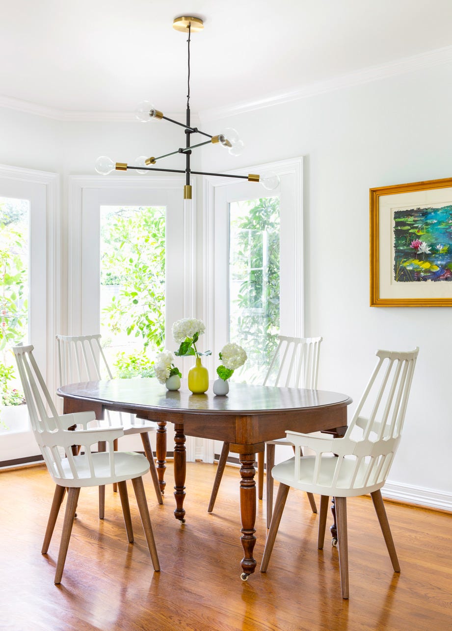 white dining room with an antique dining set and modern light fixture
