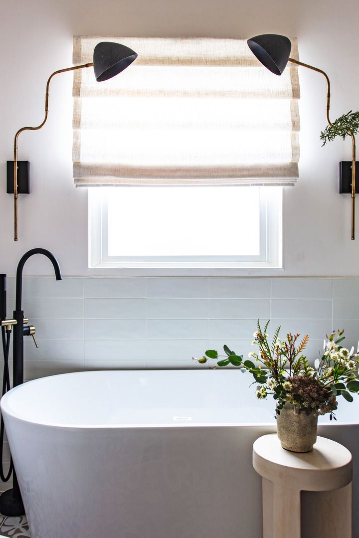 1930s spanish revival home in los angeles designer candace shure bathroom window framed with sconces, bright room, bathtub, the sconces are from architects design, a turkey based etsy seller