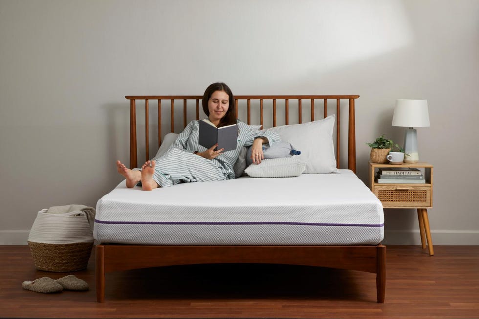 a person lounging on a mattress reading a book