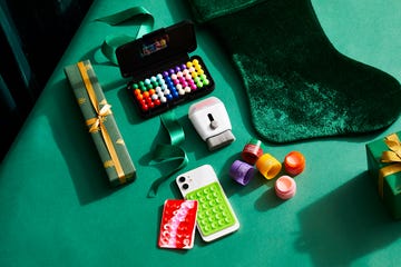 stocking stuffers on green surface including gifts a smartphone and beauty products