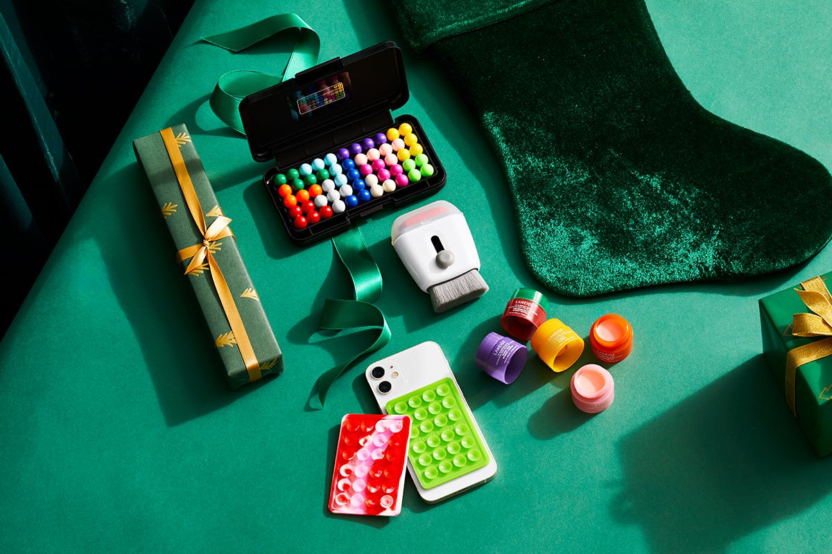 stocking stuffers on green surface including gifts a smartphone and beauty products