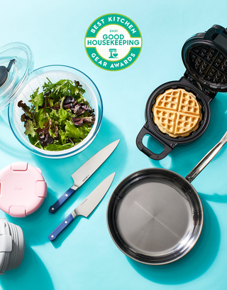 above view shot of kitchen appliances knives, frying pan, salad bowl and waffle maker with good housekeeping kitchen gear awards logo