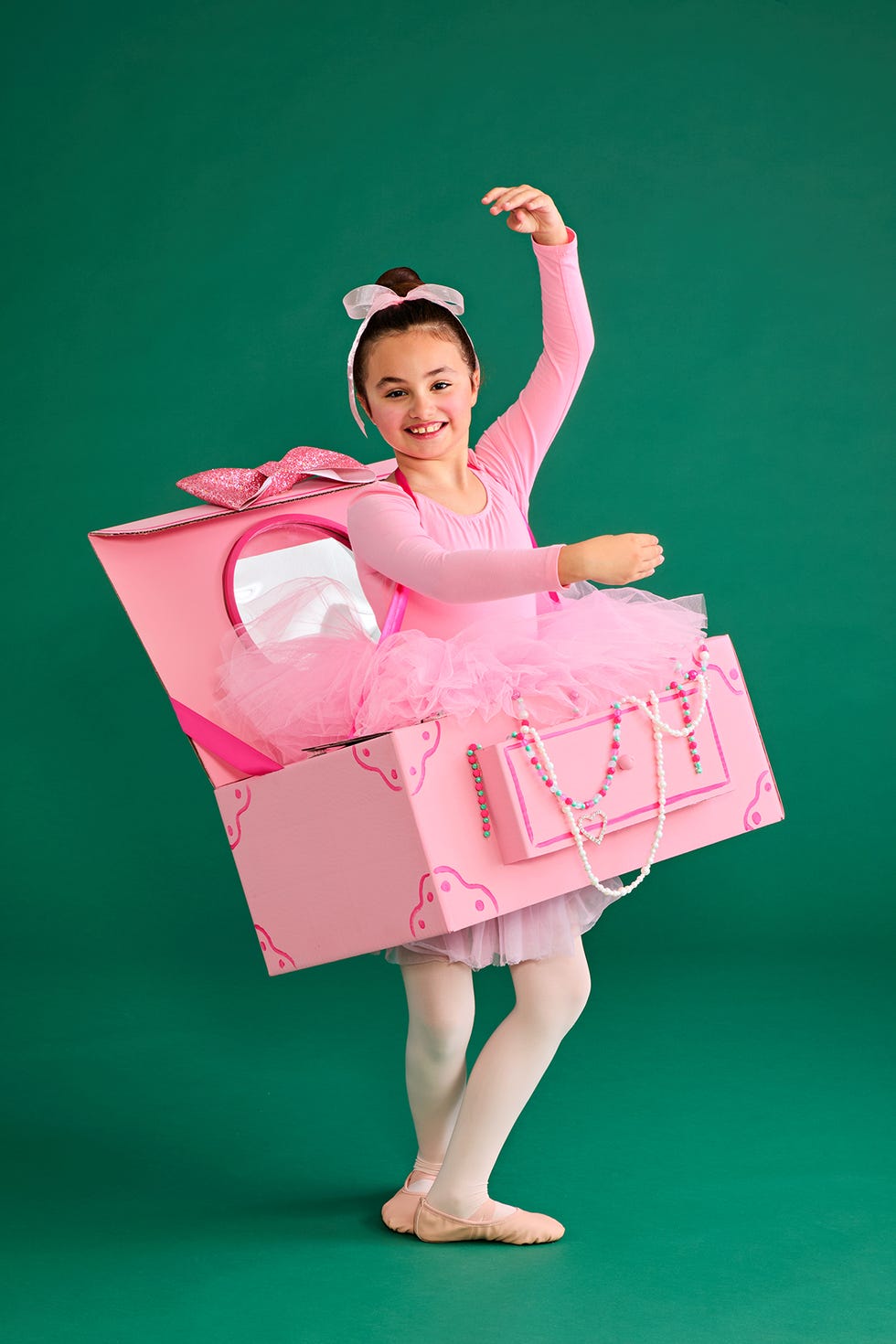 a child in a ballet costume with a large pink gift box costume