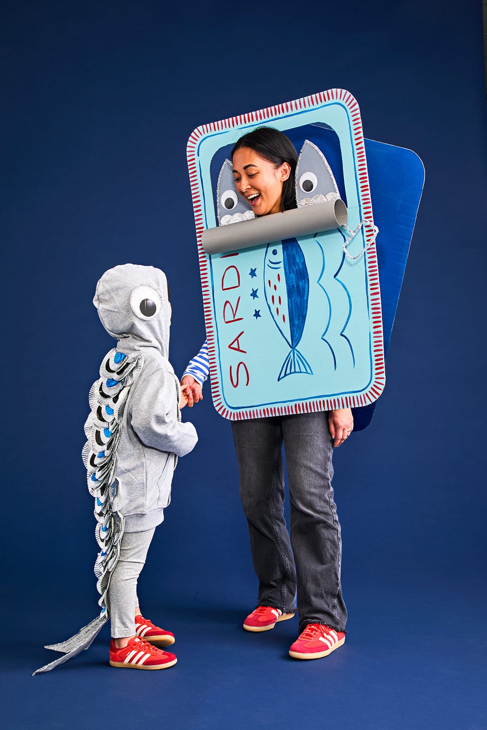 a child dressed as a sardine and an adult wearing a sardine can costume interact