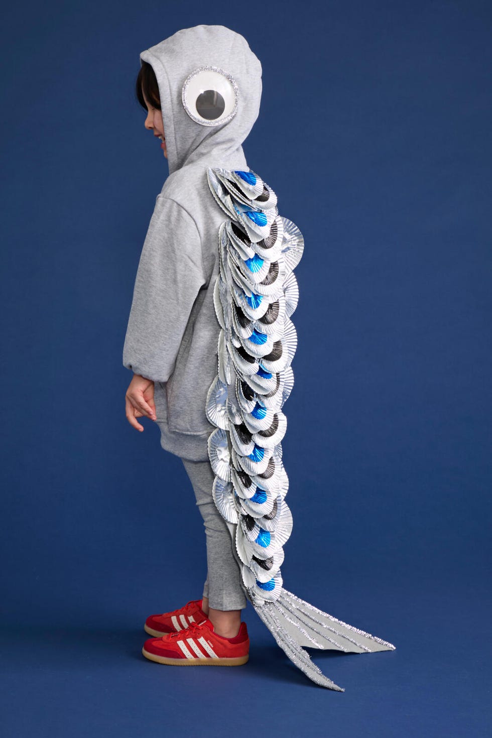 a child dressed in a creative fish costume featuring a gray hoodie and silvery scales