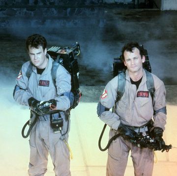 three ghostbusters stand with proton packs at the ready