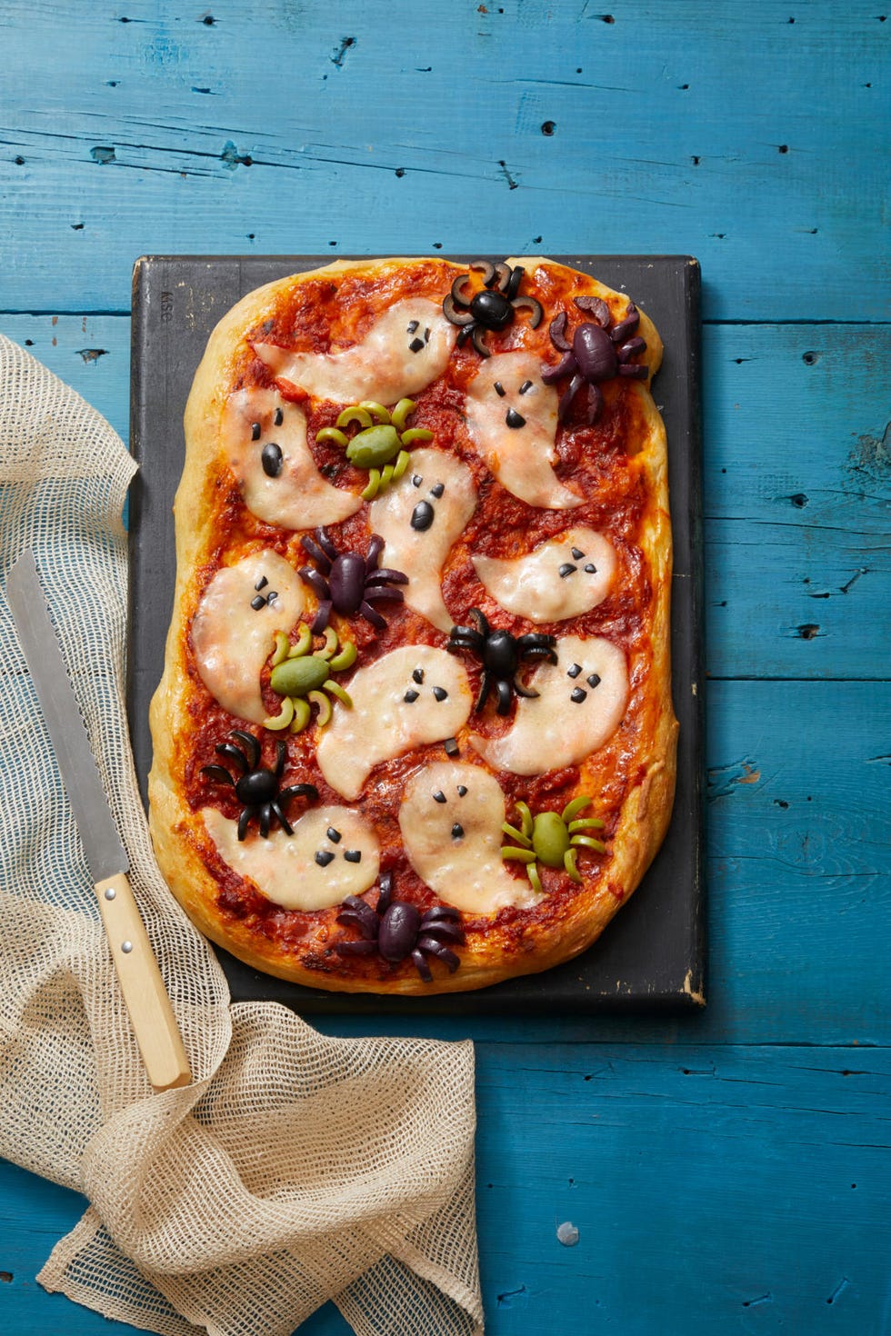 pizza with slices of ghost shaped cheese and spiders made out of olives