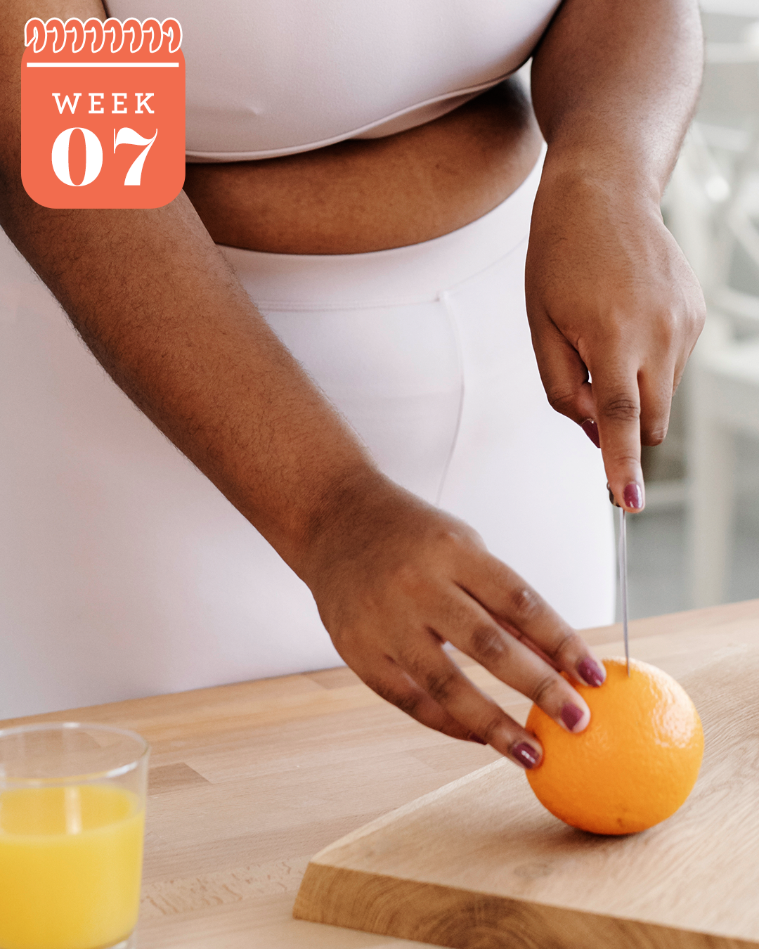 black woman in workout clothes cutting orange