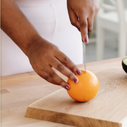 black woman cutting orange on cutting board
