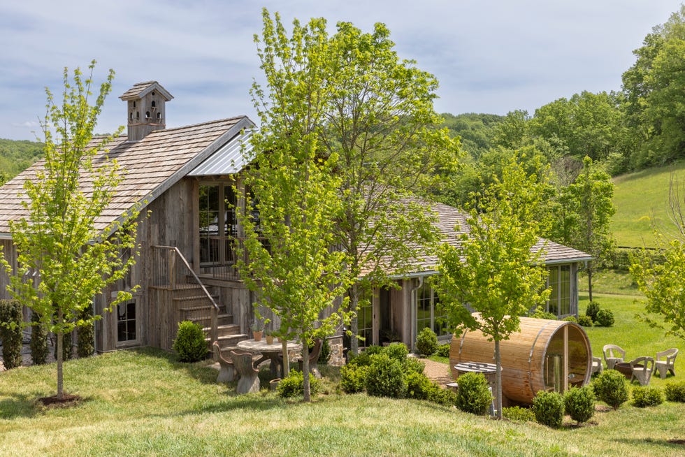exterior of log cabin with green trees and a sauna structure