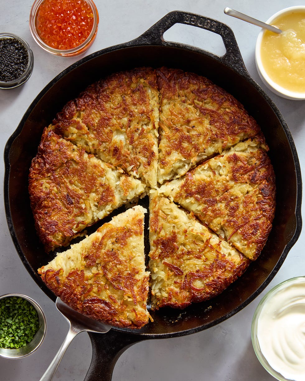 large latke in a skillet with applesauce, caviar, creme fraiche