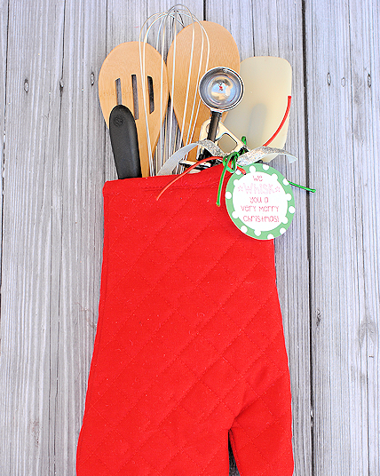a red oven mitt filled with assorted cooking utensils
