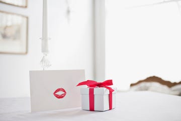 white gift box with thin red ribbon bow on old wood table with paper card  Stock Photo