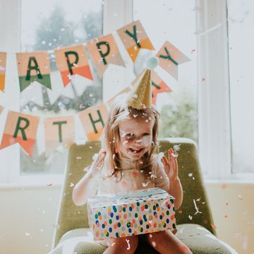 cute young girl enjoying her birthday celebrations in a decorated home environment focus on falling paper confetti space for copy