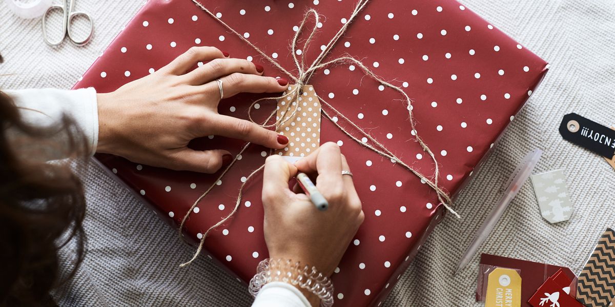 woman writing on gift tag on top of wrapped gift