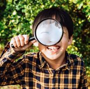 young boy holding microscope up to eye