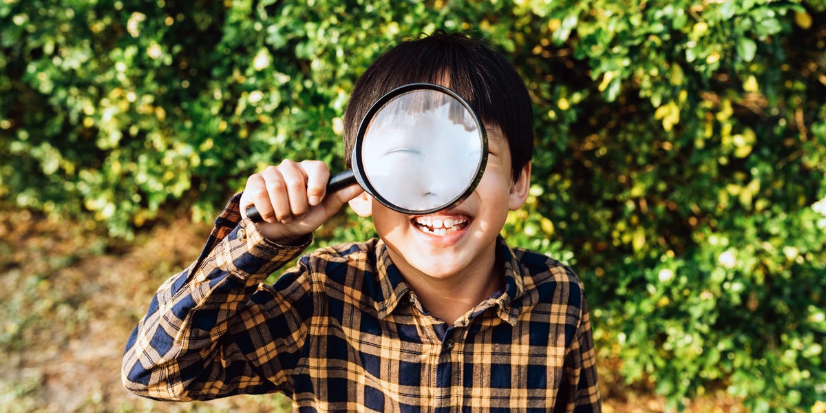 young boy holding microscope up to eye