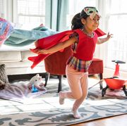 girl playing in superhero cape and butterfly mask