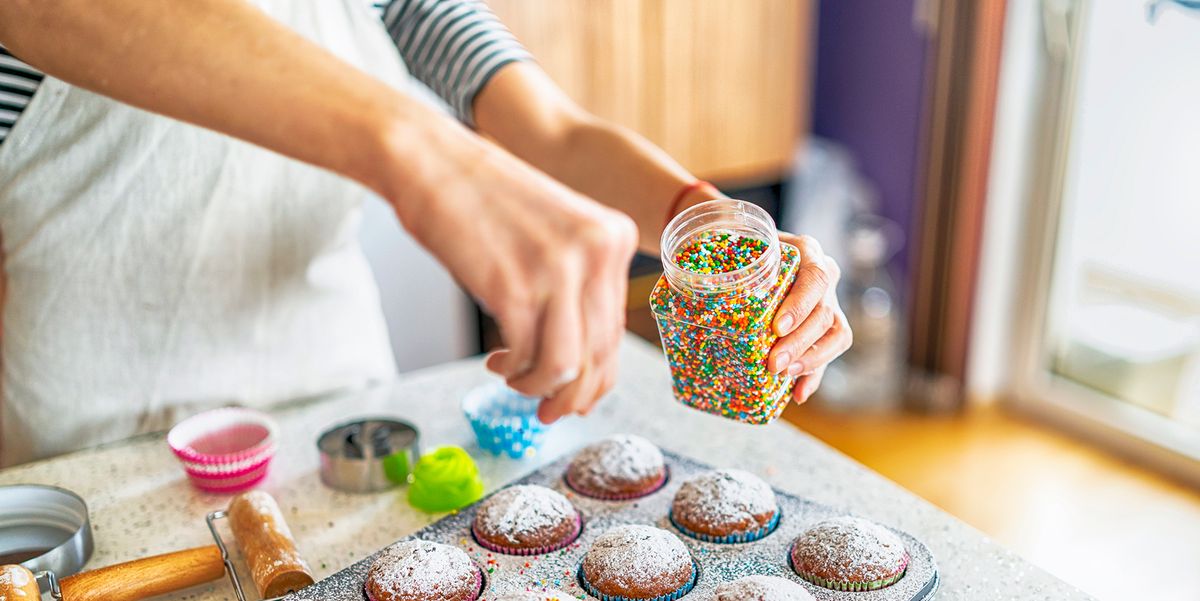 baker adding sprinkles to cupcakes