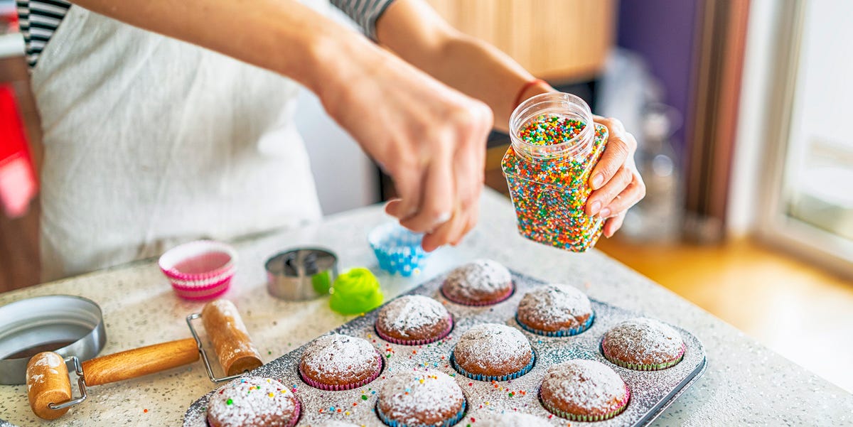 baker adding sprinkles to cupcakes