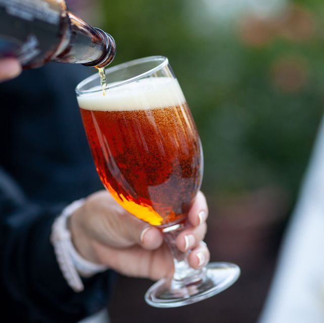 person holding glass while beer is poured