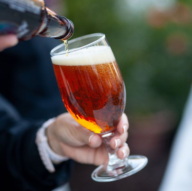 person holding glass while beer is poured