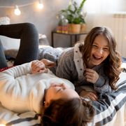 two tween girls laughing on bed with string lights