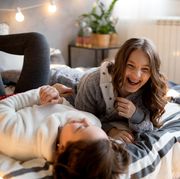two tween girls laughing on bed with string lights